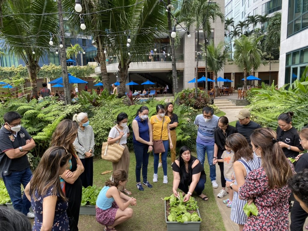 Rockwell residents and children gathered around a community hydroponic garden bed in Manila
