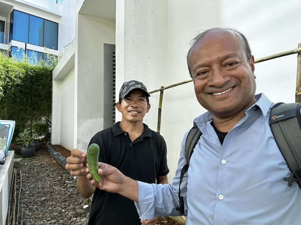 Sohail Hasnie and a grower holding up a cucumber grown on site